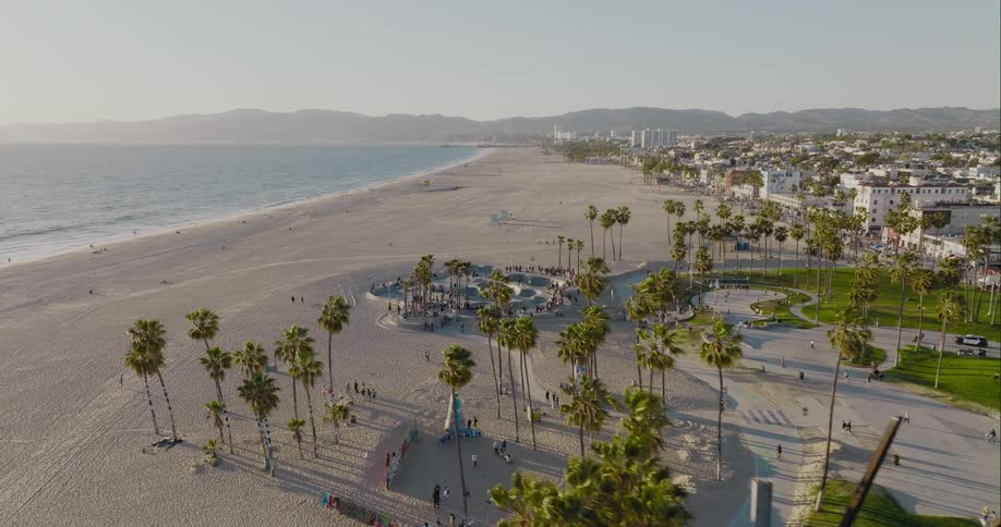 Palm trees and a skateboard park on the beach near the ocean with mountains in the distance