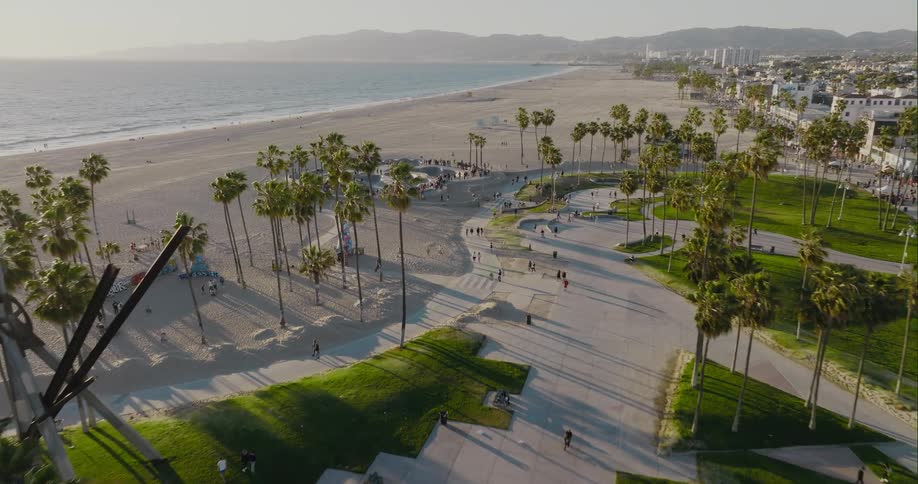 Aerial view of a group of people skateboarding on a skate park on the beach at evening