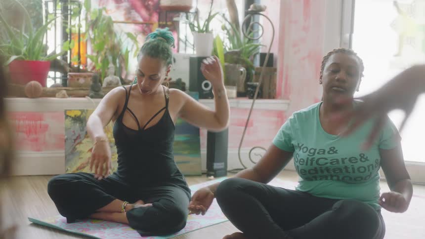 Group of women sitting cross legged over mats on the floor relaxing their bodies