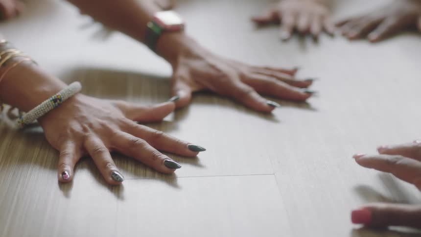 A group of women put their hands on a table and tap their fingers