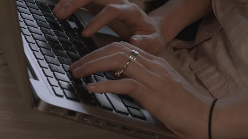 Close up shot of a woman typing on a laptop