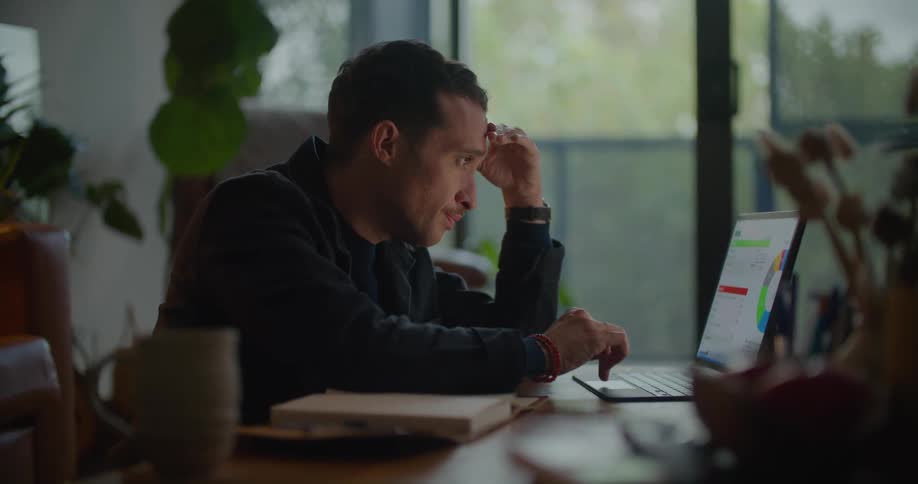 A man is sitting at a table working on a laptop computer