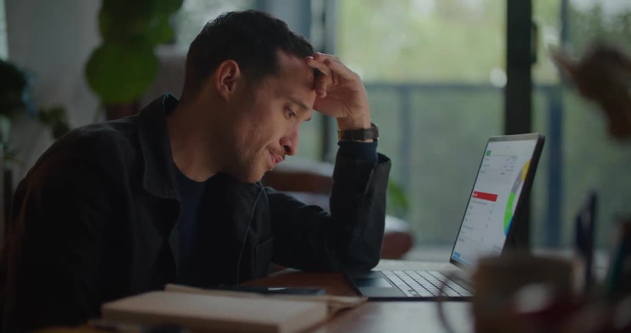 Tired man sitting in front of a laptop at home trying to concentrate on work or study