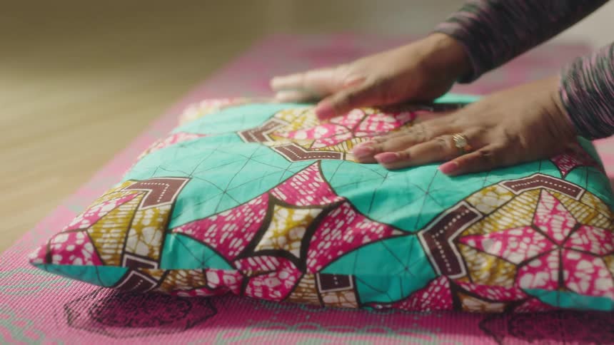 A woman smooths the top of a pillow and fluffs it
