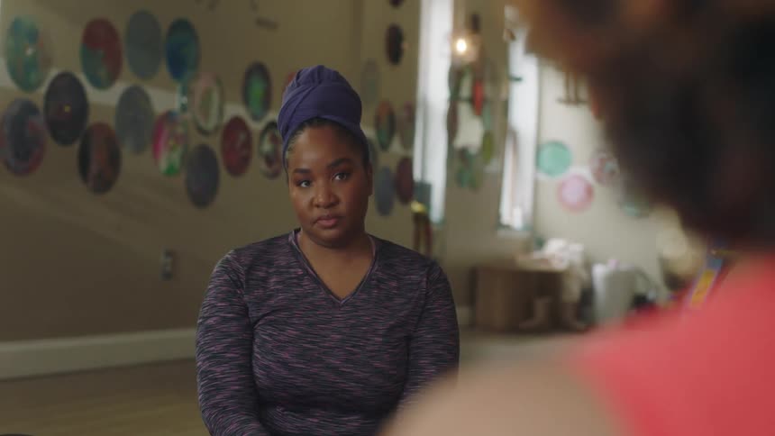 One woman talks animatedly as another woman sits across from her listening and nodding