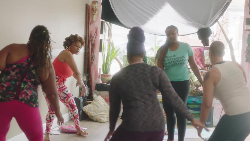 An instructor leads a group of women in swaying and stretching at a studio