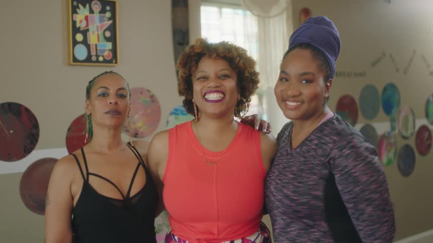 Group of friends standing on the living room at home smile at the camera while hugging