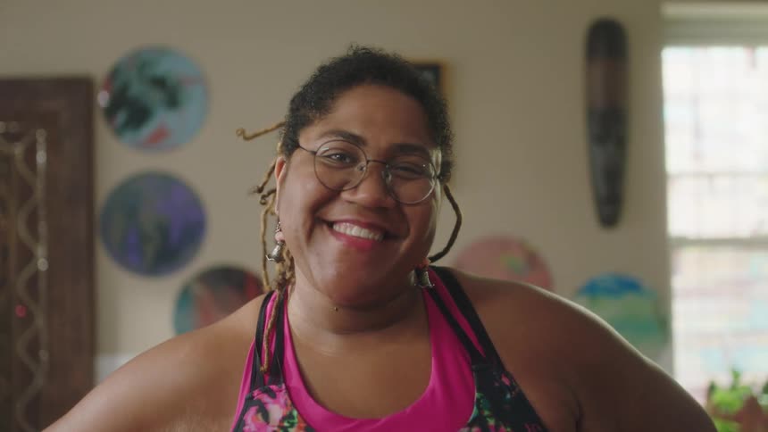 A woman smiles into the camera while standing indoors during the day