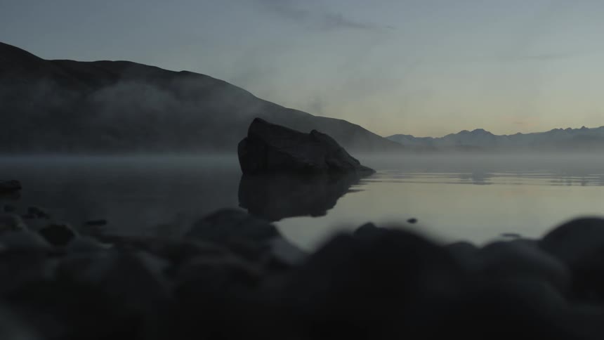 A large rock protrudes from a lake