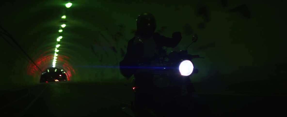 Biker with helmet and jacket rides motorcycle through tunnel at night