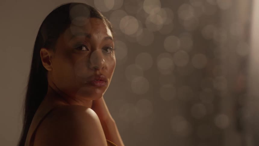 Model looking around behind a wet window with water drops running down