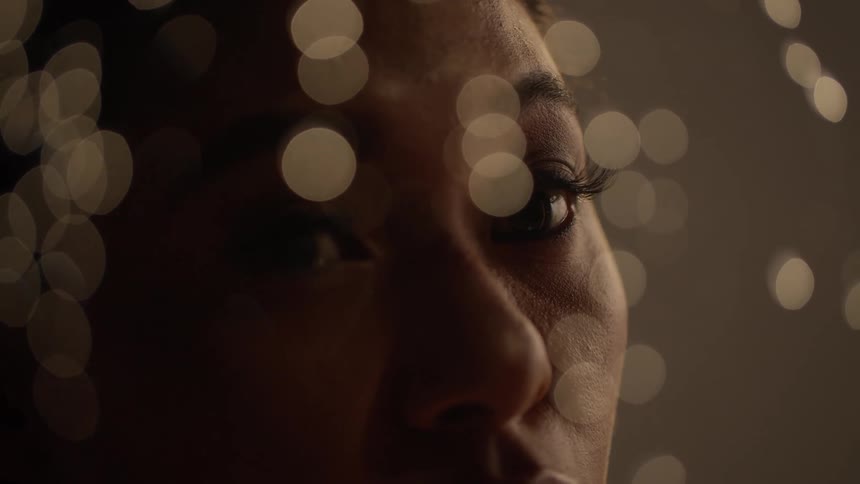 Woman with long lashes looks through nearby window a raindrops flow down the glass