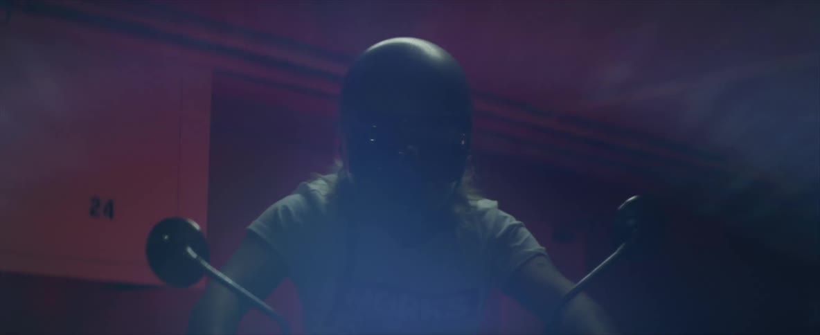 Male biker with long hair and helmet rides motorcycle indoors at night