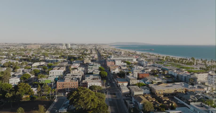 Aerial view of a medium coastal city with small buildings next to a beach on a sunny day