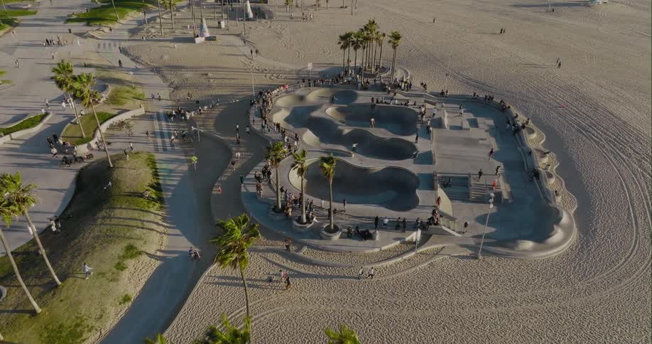 Aerial view of a group of people skateboarding on a skate park on the beach at evening