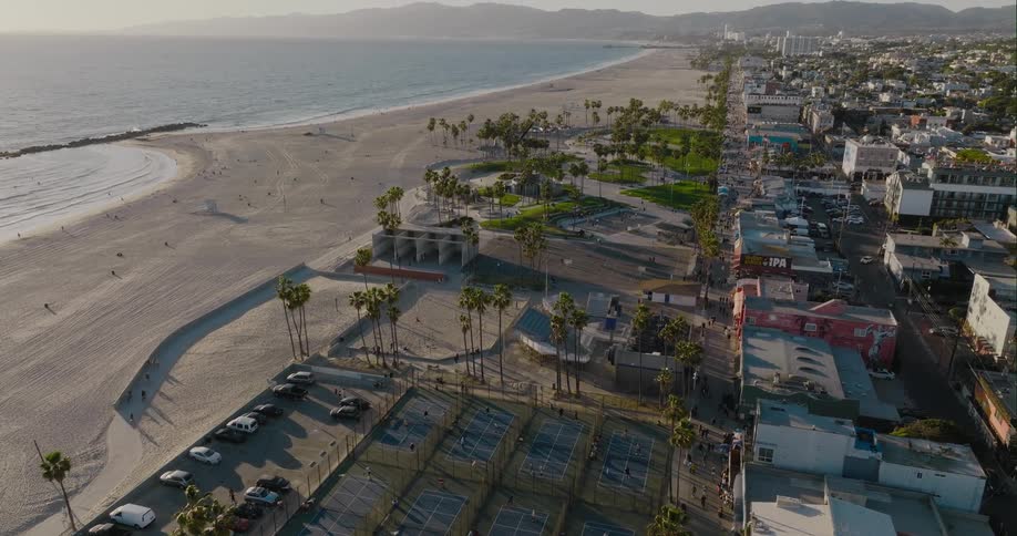 People uses the sports and recreational facilities on a large beach in a city during the day