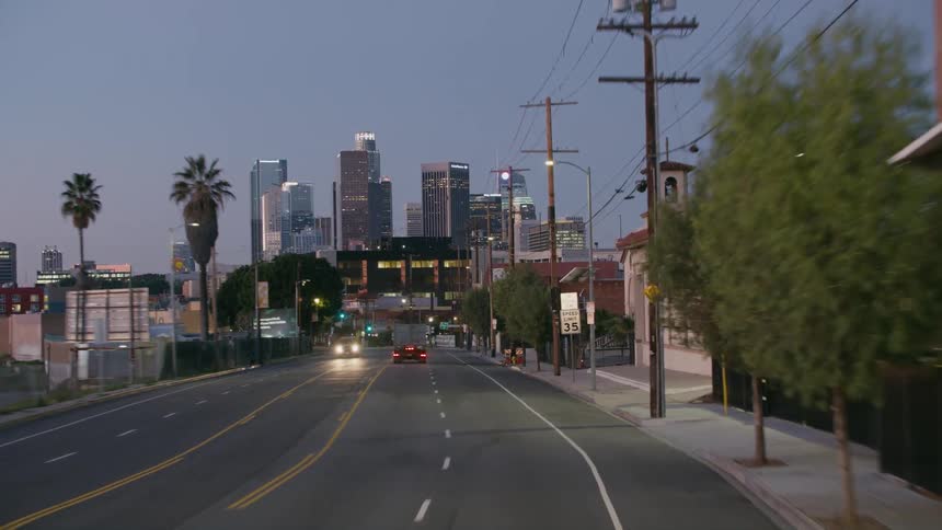 Traveling along a city street of a suburb in the evening with a skyline in the distance