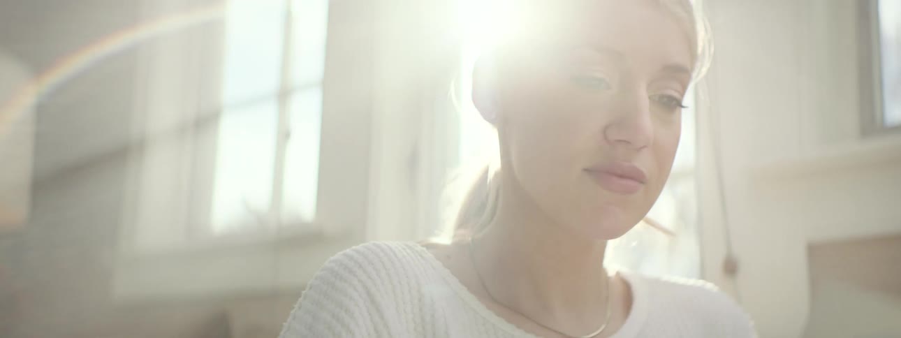 A woman relaxes in cozy, bright living room and reads a book on a sunny day