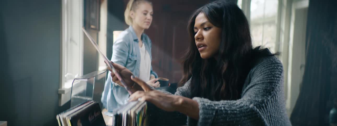 Woman goes through vinyl records as a friend watches