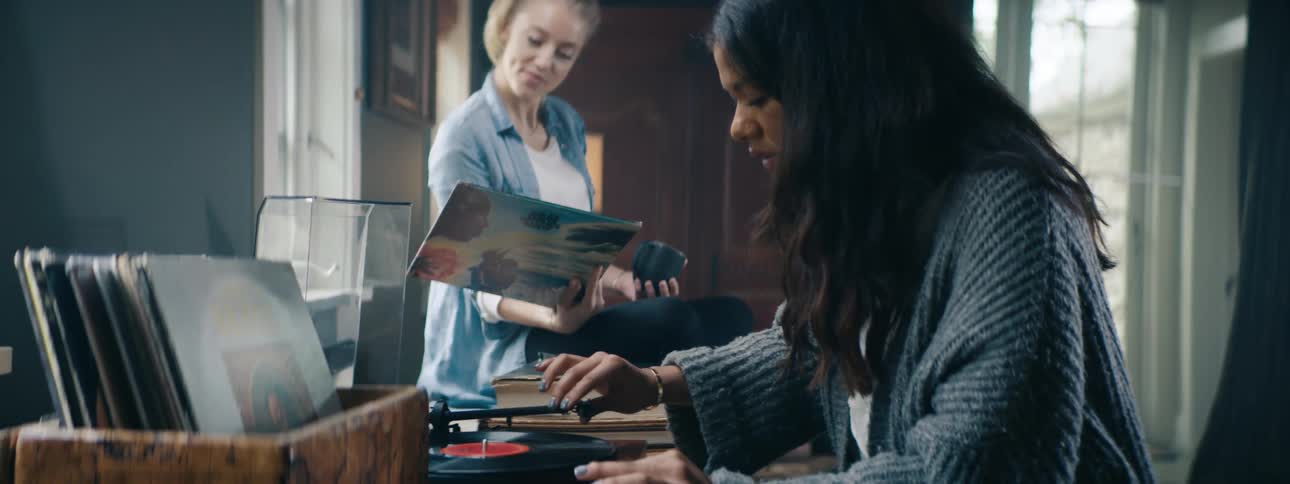 Friends hanging out looking at vinyl collection and putting a record on to listen