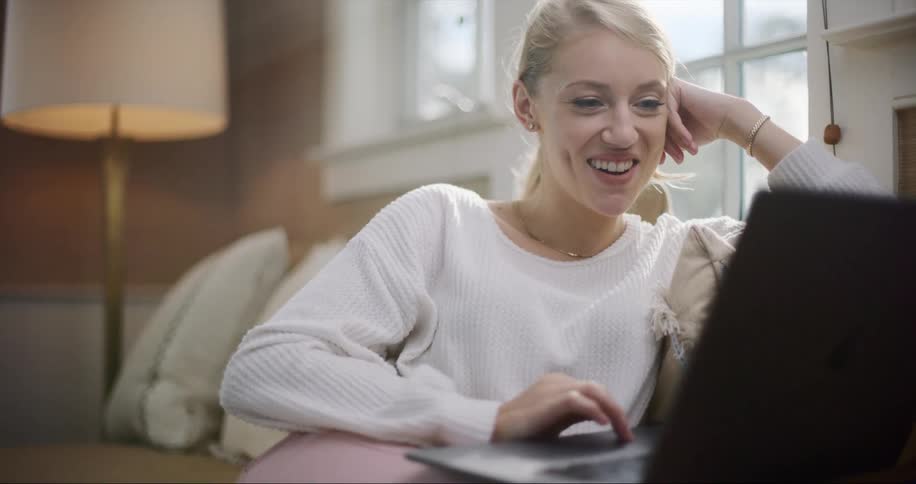 Young woman working from home has a virtual meeting and laughs at the screen