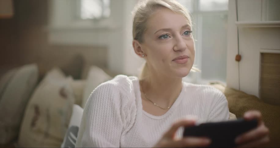 A woman sitting in a room using a smartphone