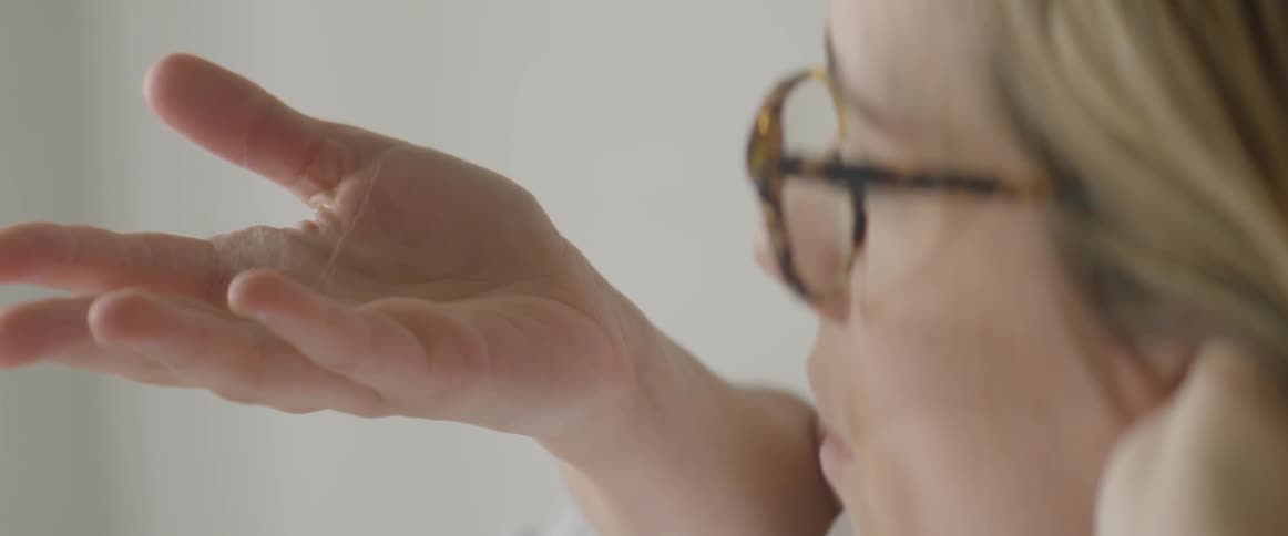 Woman opening her clenched hand and blowing a small wad of hair from her palm