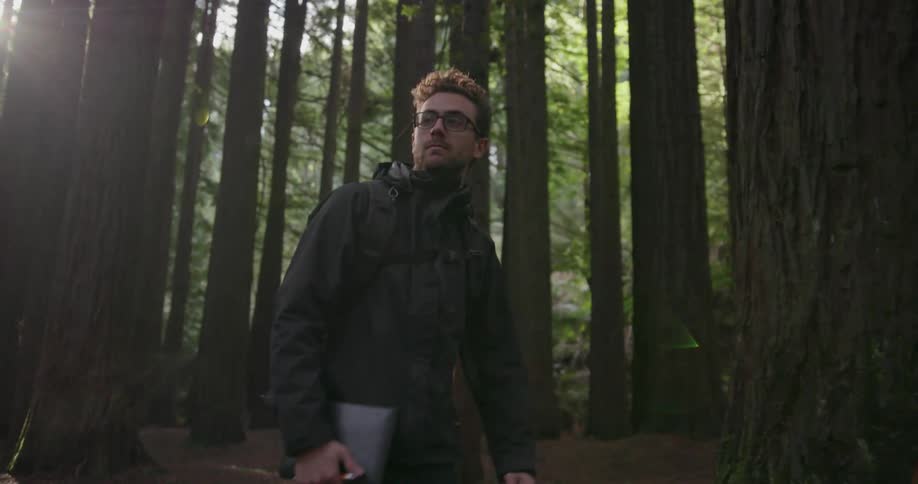 A man is hiking in the woods holding a book