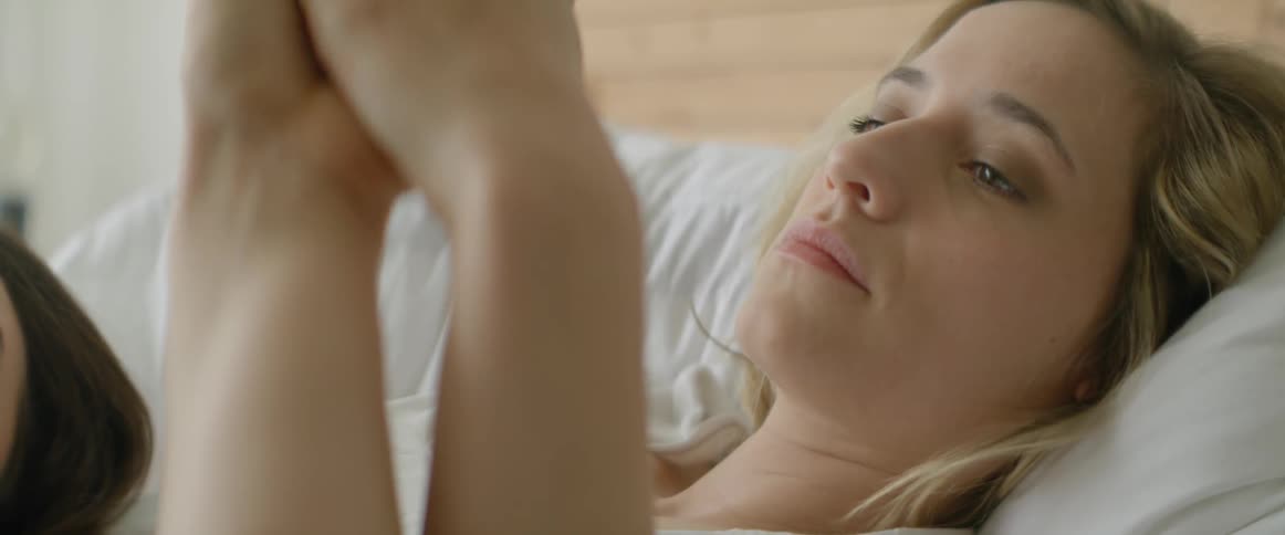 A man and woman hold hands in bed