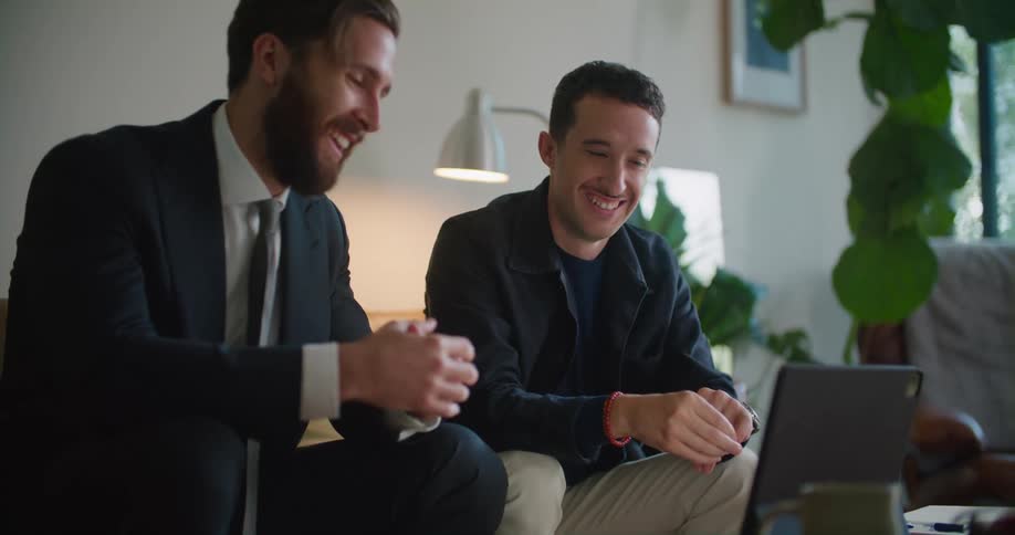 Two men having a business meeting in the living room looking at a tablet