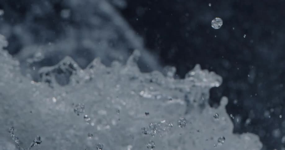 Close up of waterfall cascading down as water droplets fly into the air