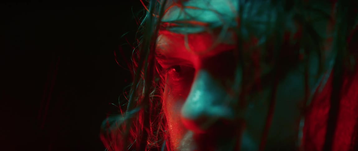 Blue and red lights color plains of man standing outdoors in the rain with disarrayed hair