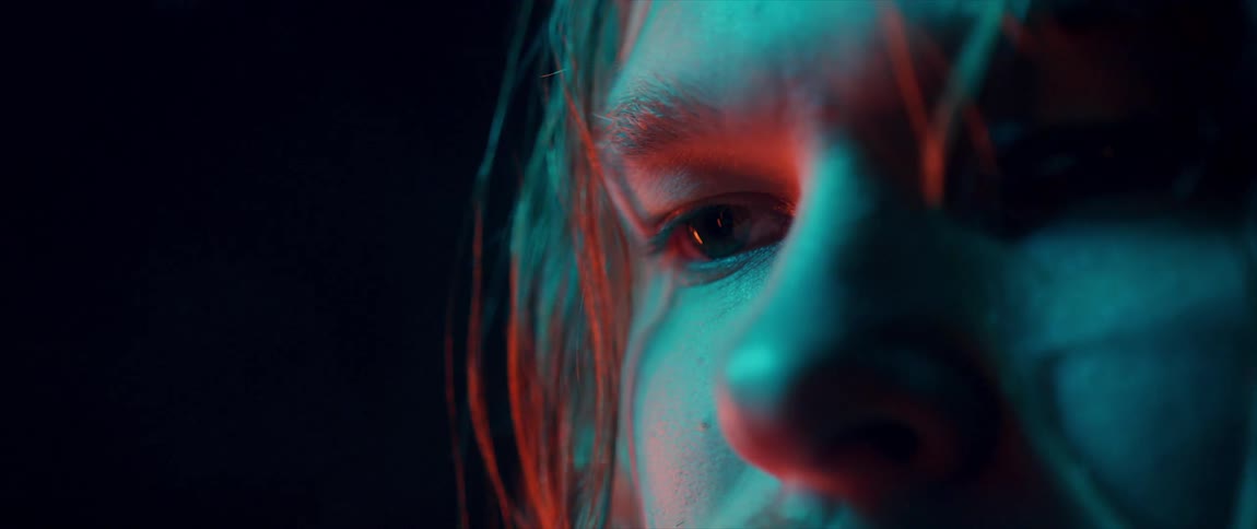 Close up of mans face with long hair in red light in dark room