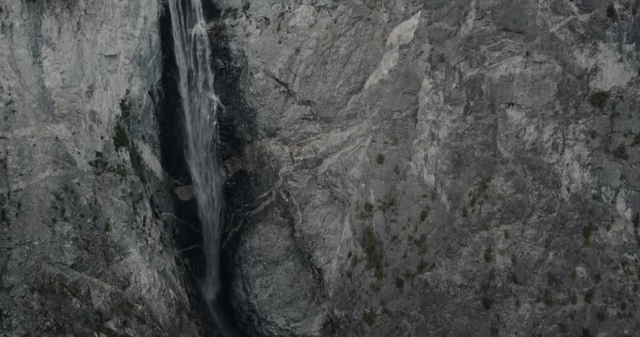 A waterfall cascades down a cliff into a canyon during the day