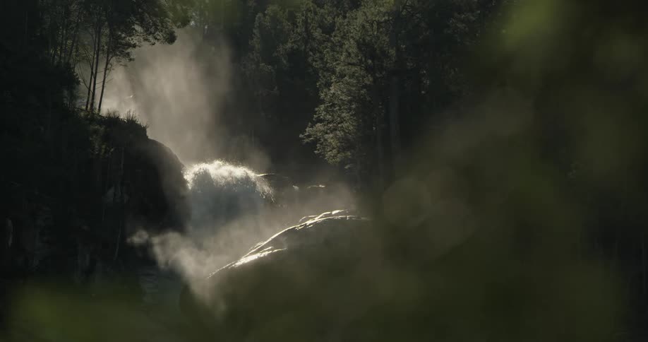 Turbulent water crashes over waterfall and creates mist in the air