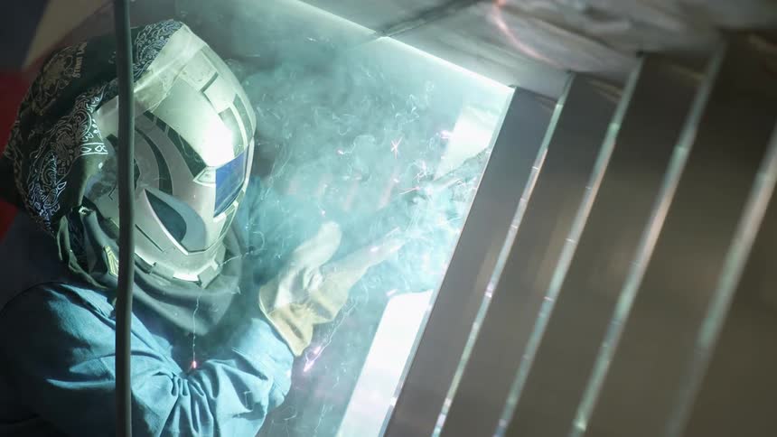 Welder wears protective equipment as he welds