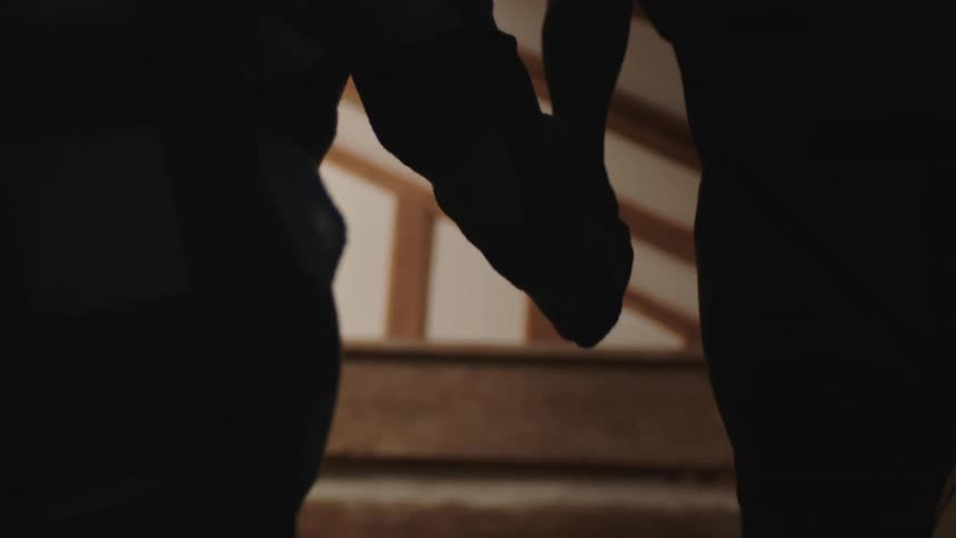 Man and womon holding hands and going upstairs are silhouetted