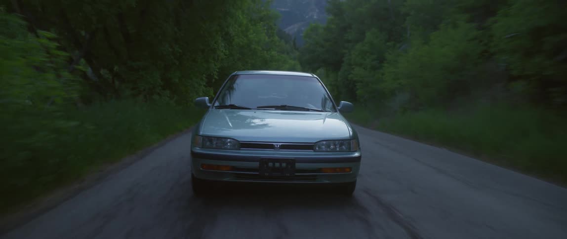 An automobile is traveling on a forest road