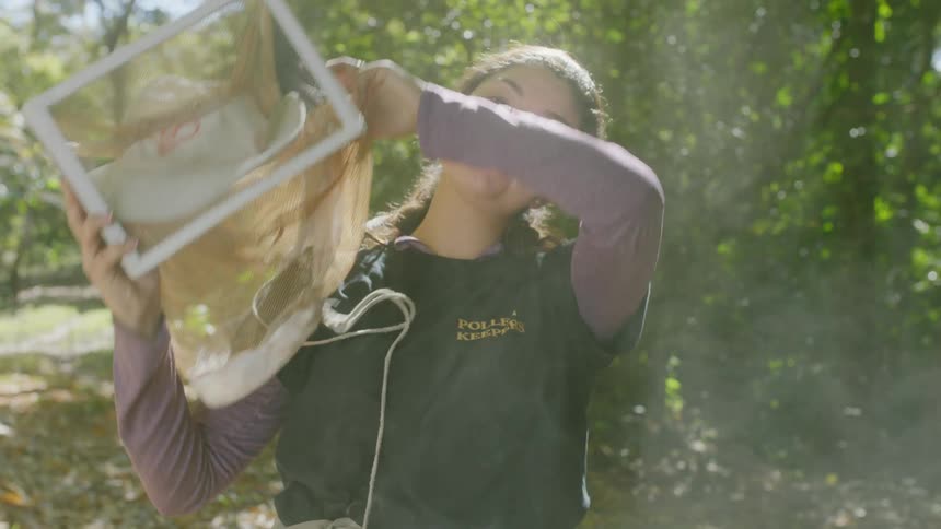 A beekeeper removes her mask
