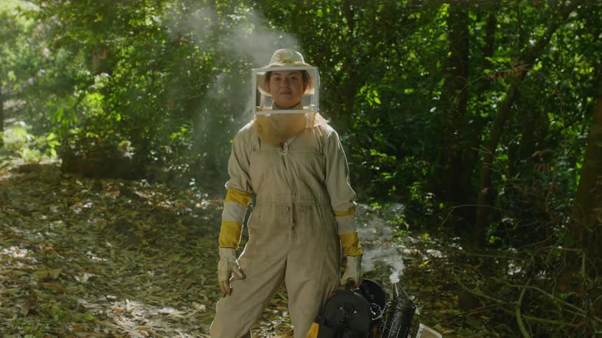 A beekeeper is posing outside