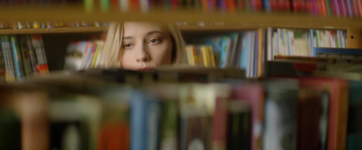 A woman is looking through books in a library