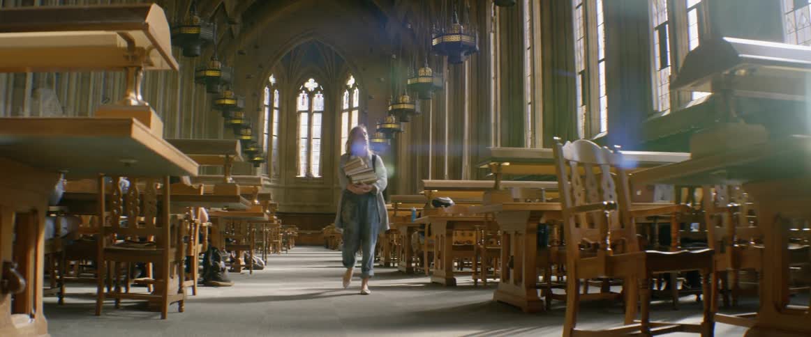 A woman carrying books through a library