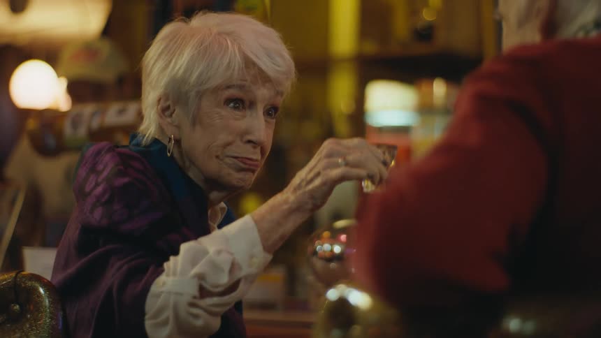 Elderly happy woman drinking shots with a friend at a bar
