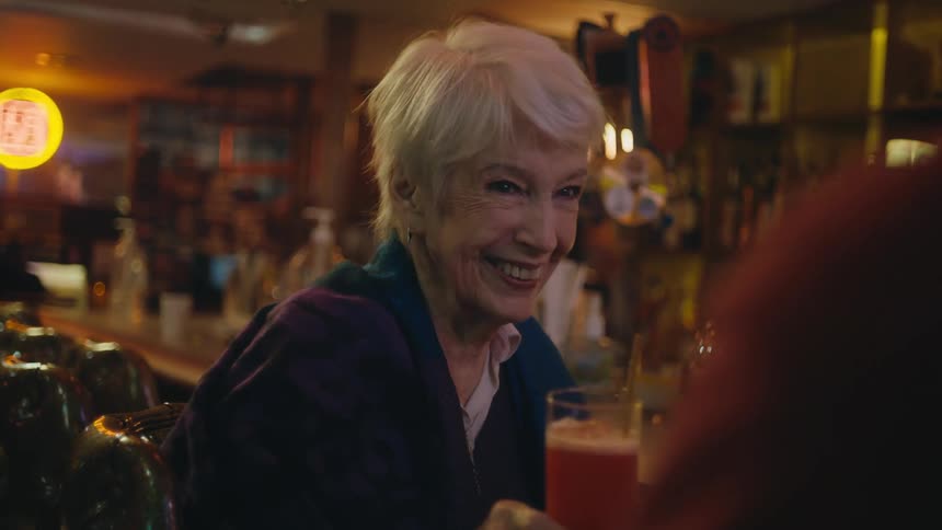 A woman is having an alcoholic drink at a bar counter