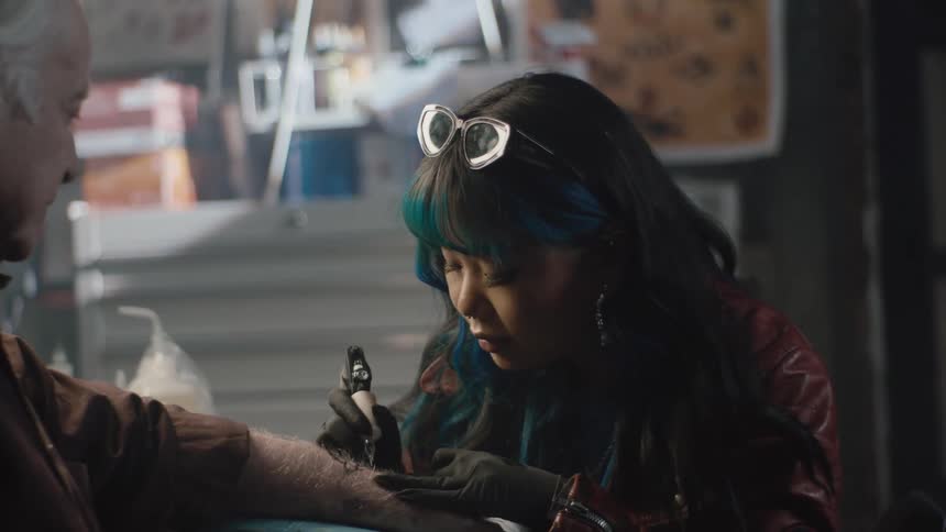 Tattoo artist works on clients arm with a tattoo gun