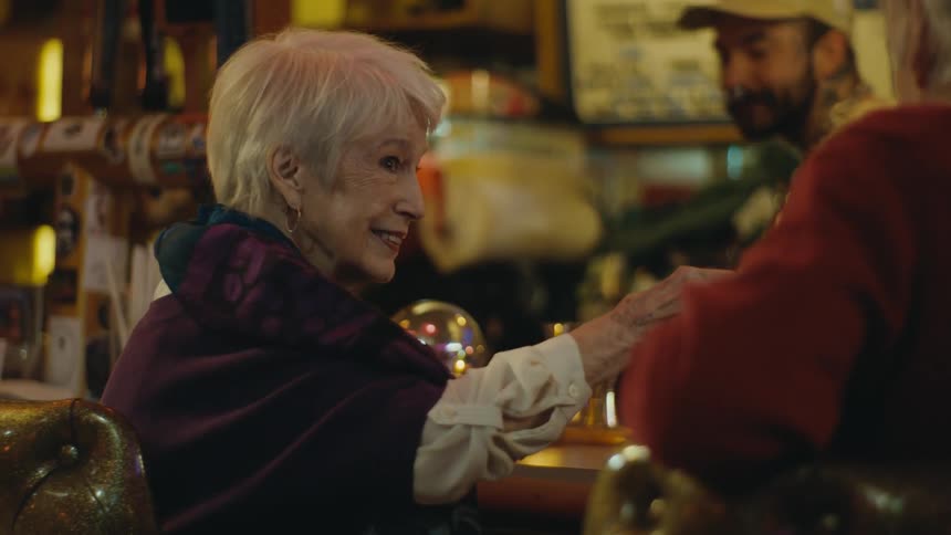 Two excited seniors sitting at the bar counter making a toast and drinking a shot together