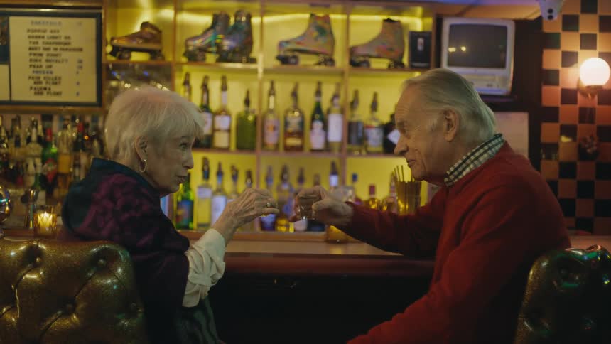 An elderly man and woman take shots together