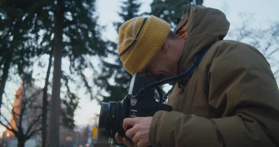 A photographer uses sign language to communicate with someone out of frame before using a large camera to take a photograph