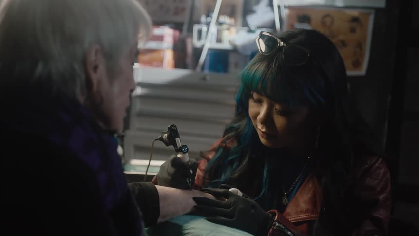 A person is getting tattooed by a woman indoors