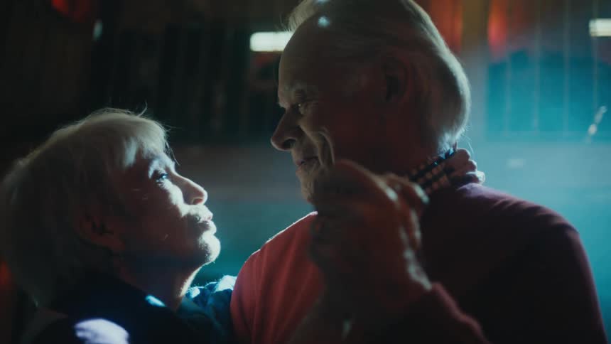 An elderly couple dancing and kissing